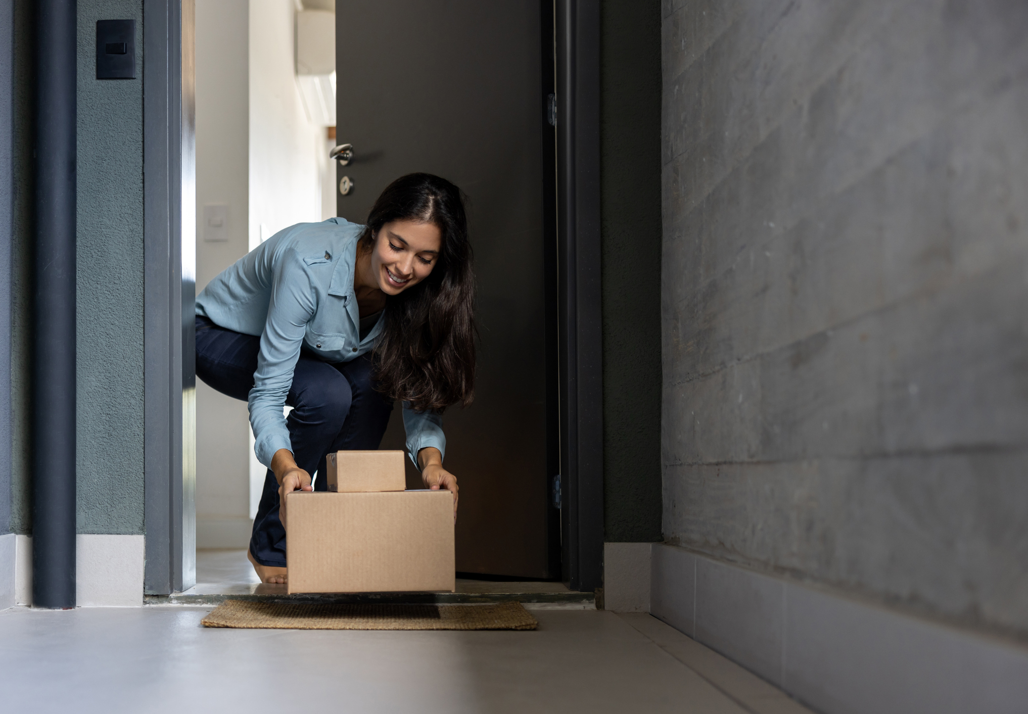 Woman retrieves care package at her door.
